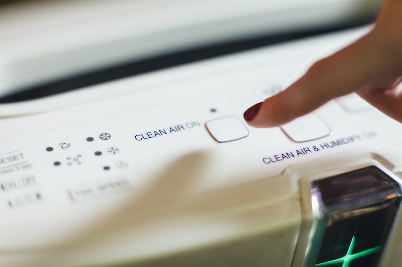 Close-up of female hand turning on an air purifier and ionizer