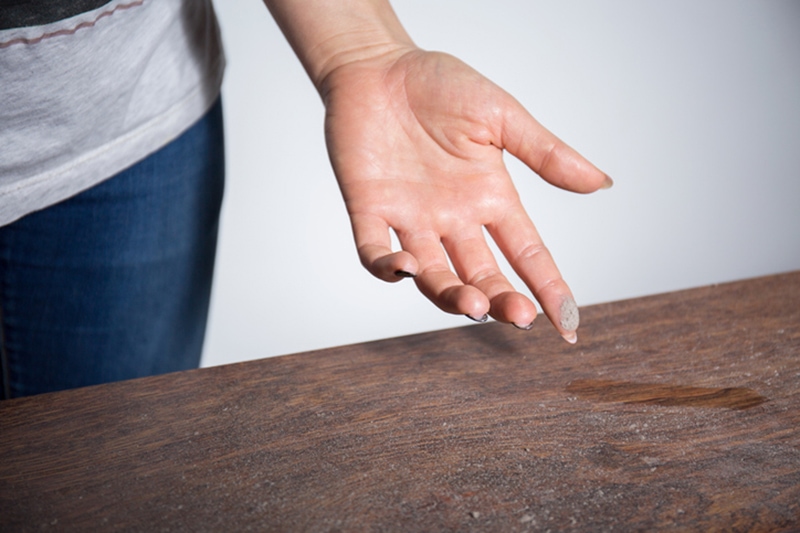 Person with dust on their finger after wiping a table.