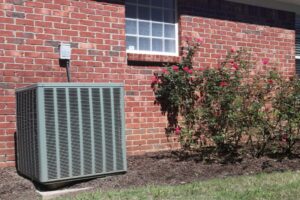 Air conditioner unit at a home with rose bushes.