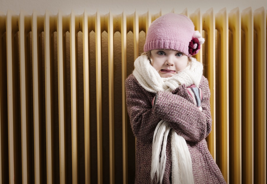 Little girl trying to stay warm inside home and showing her family that it might be time to buy a new furnace.